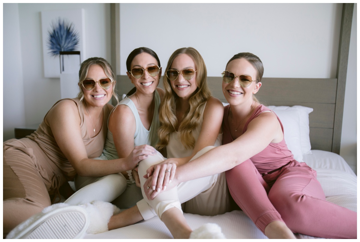 bridesmaids smile with heart shaped glasses and personalized tank tops and jogger pants for a unique bridesmaid getting ready look