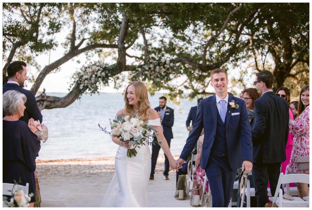 bride and groom descend down aisle as husband and wife during beach wedding ceremony in key largo florida 